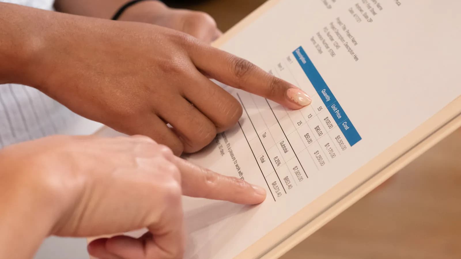 Two fingers point at line items on a printed invoice.